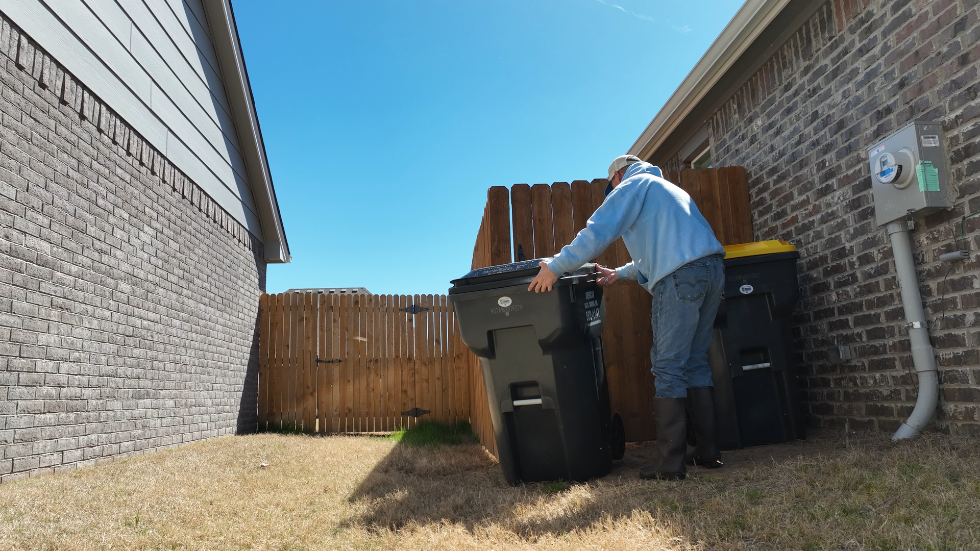 An image of Okie bin cleaners returning a set of clean bins to their location in a customer's yard